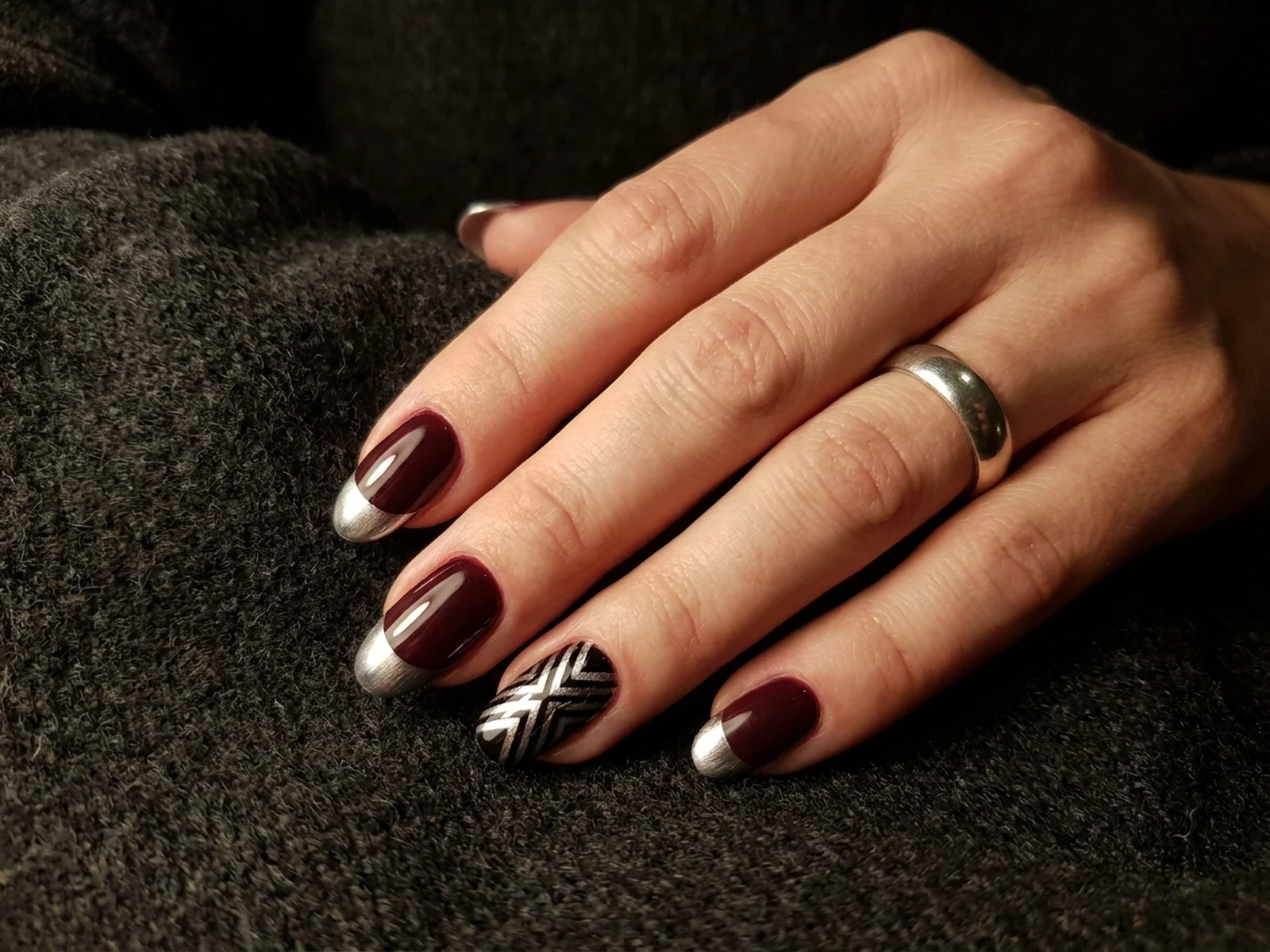 Burgundy oval manicure with silver chrome tips and geometric accent nail